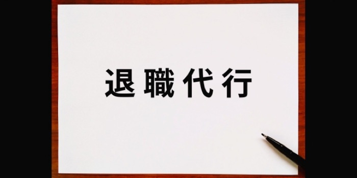 「退職代行」と書かれた紙とペン