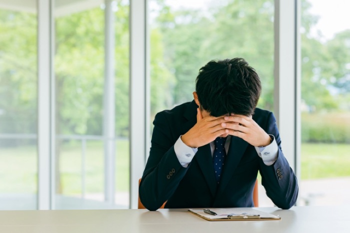 デスクで頭を抱える会社員のイメージ
